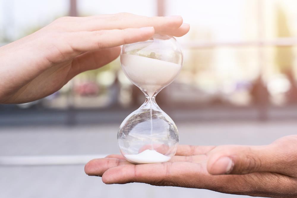 An hourglass with sand being held by two hands